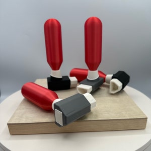 May include: Five red and gray plastic inhalers on a wooden surface. The inhalers have a cylindrical shape with a gray mouthpiece and a red body.