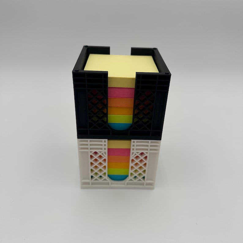 May include: A black and white crate-style dispenser filled with colorful sticky notes. The notes are arranged in a rainbow pattern.