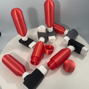 May include: A set of six red and white plastic bottle stoppers with black bases. The stoppers are shaped like small cylinders with a threaded top and a white ring around the base. The bases are square and have a black finish.