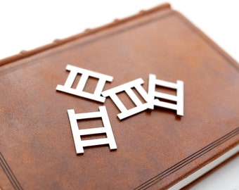 May include: Four small white wooden ladders on a brown leather-bound journal.