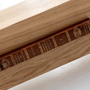May include: A vintage book titled "Selections from the Writings of Henry D. Thoreau" is resting on a wooden shelf.