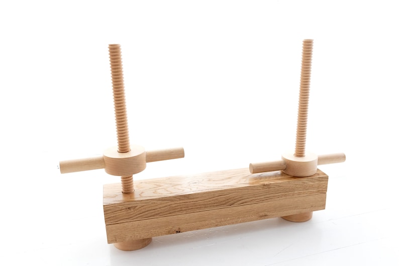 May include: A wooden clamp with two adjustable screws and a long wooden base. The clamp is made of natural wood and has a rustic look.