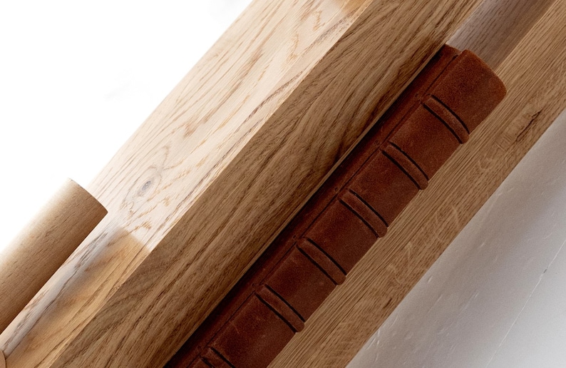 May include: Close-up of a wooden shelf with a brown leather-bound book resting on top. The shelf has a natural wood grain and is made of solid wood.