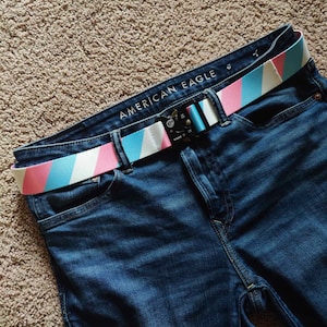 May include: Blue jeans with a striped belt that says "AMERICAN EAGLE" on the buckle.