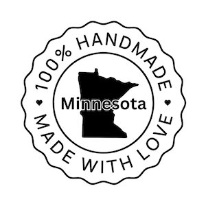 Op de afbeelding: Een zwarte en witte ronde stempel met de tekst "100% Handgemaakt met liefde" en een omtrek van de staat Minnesota. De tekst "Minnesota" staat binnen de omtrek van de staat.