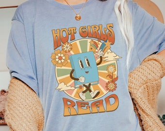 May include: A light blue t-shirt with a retro graphic of a book character with the text "Hot Girls Read".