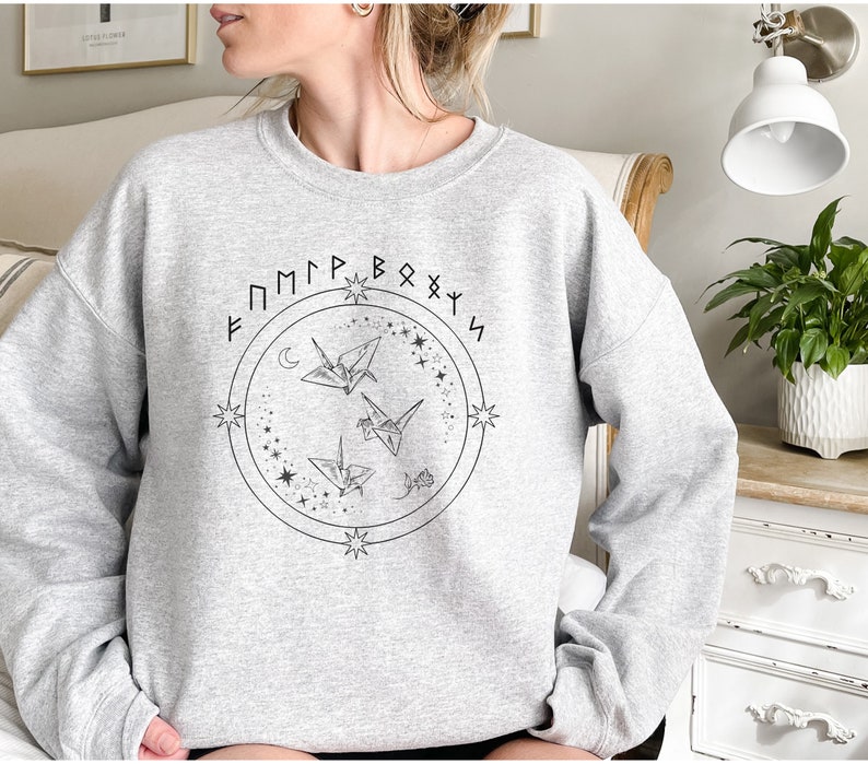 May include: Gray sweatshirt with a graphic of three origami cranes flying in a circle with stars and the text "F M M P R B O X Y S" around the circle.