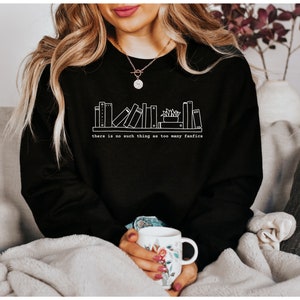 May include: Black sweatshirt with a white graphic of a bookshelf and the text "there is no such thing as too many fanfics". The sweatshirt is made of a soft material.