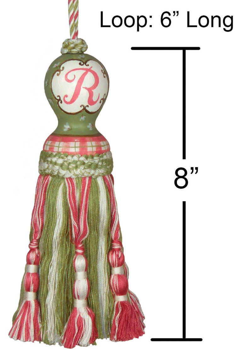 Puede incluir: Borla verde y rosa con una parte superior de madera pintada con la letra "R" en rosa. La borla mide 8 pulgadas de largo y tiene un lazo de 6 pulgadas.