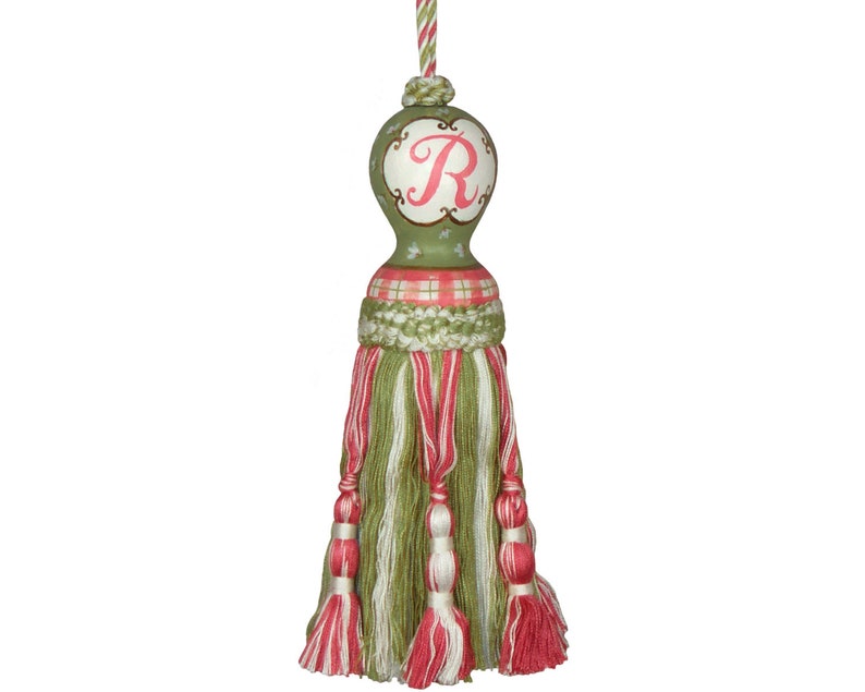 Puede incluir: Borla verde y rosa con un patr&oacute;n de cuadros verde y blanco y una bola verde con una letra R rosa en ella.