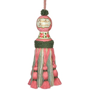 Peut inclure: Un pompon rose et vert avec un dessus rond peint qui dit "Powder Room". Le dessus a un motif à carreaux rose et blanc avec des roses vertes.
