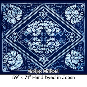 Könnte beinhalten: Ein quadratisches, indigogefärbtes Textil mit weißem Blumenmuster und dekorativen Bordüren. Der Text "Indigo Shibori" ist abgebildet, zusammen mit den Maßen 150 cm x 180 cm und "Hand Dyed in Japan".