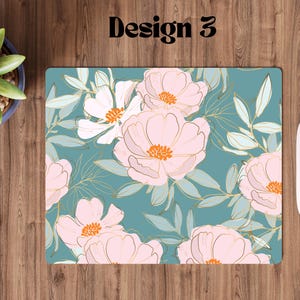 May include: A teal blue mousepad with a floral design featuring pink and white flowers with gold accents.