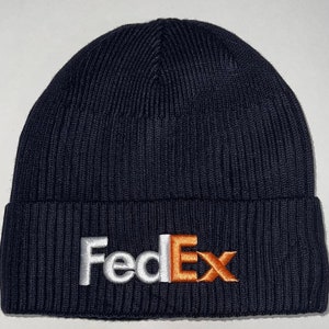May include: A navy blue knit beanie with a white and orange "FedEx" logo embroidered on the front.