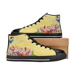 K&ouml;nnte beinhalten: Hohe Canvas-Sneaker mit gelbem Hintergrund und einem Design von Schneewittchen und den sieben Zwergen. Die Schuhe haben schwarze Schn&uuml;rsenkel, Sohlen und Zierleisten. Die Worte "Snow White" sind kursiv auf der Seite geschrieben.