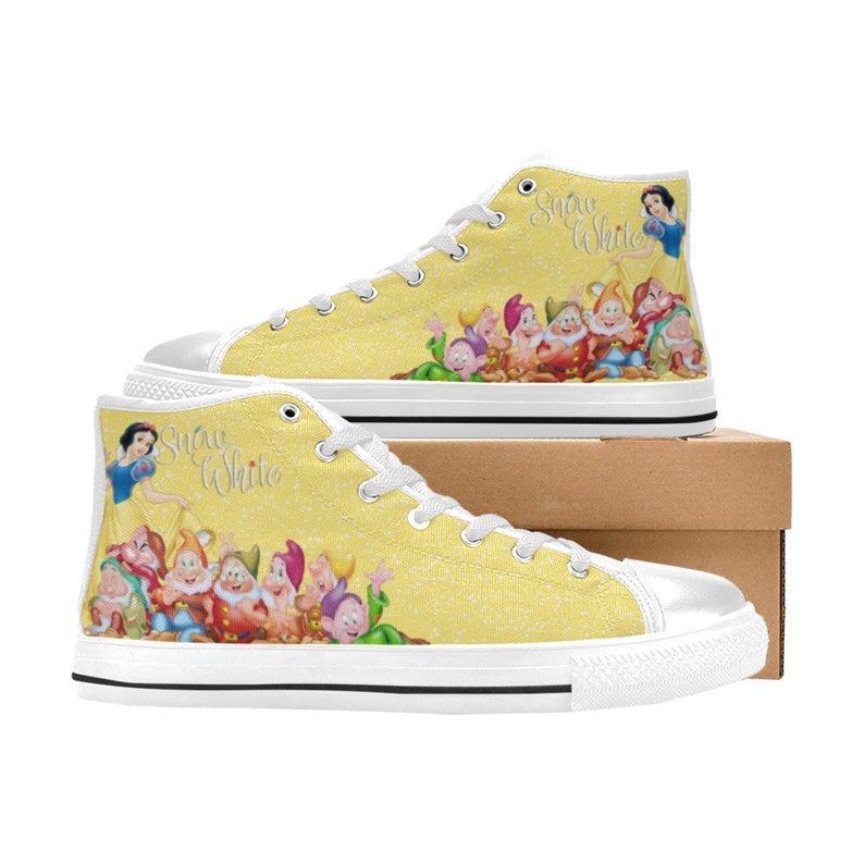 K&ouml;nnte beinhalten: Hohe Canvas-Sneaker mit gelbem Hintergrund mit Glitzereffekt. Die Sneaker zeigen eine Grafik von Schneewittchen und den sieben Zwergen. Der Text "Snow White" steht auf der Seite. Wei&szlig;e Schn&uuml;rsenkel und Sohlen runden das Design ab.