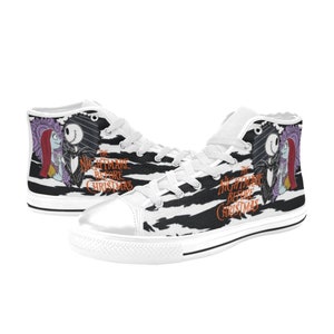 K&ouml;nnte beinhalten: Wei&szlig;e High-Top-Canvas-Schuhe mit einem schwarz-wei&szlig;en Zebra-Muster. Die Schuhe zeigen ein Motiv von Jack Skellington und Sally aus dem Film "Nightmare Before Christmas".