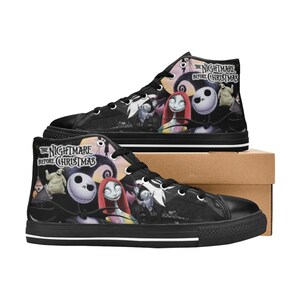 Op de afbeelding: Zwarte high-top canvas schoenen met een print van personages uit de film "The Nightmare Before Christmas". De schoenen hebben witte veters en een witte streep rond de zool.
