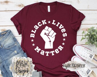 May include: A maroon t-shirt with a white graphic design that says "Black Lives Matter" with a raised fist in the center of the circle.