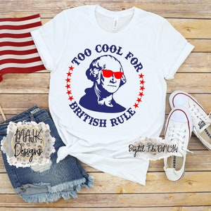 May include: White t-shirt with a blue and red graphic of George Washington wearing sunglasses and the text "Too Cool For British Rule" in a circle with red stars.