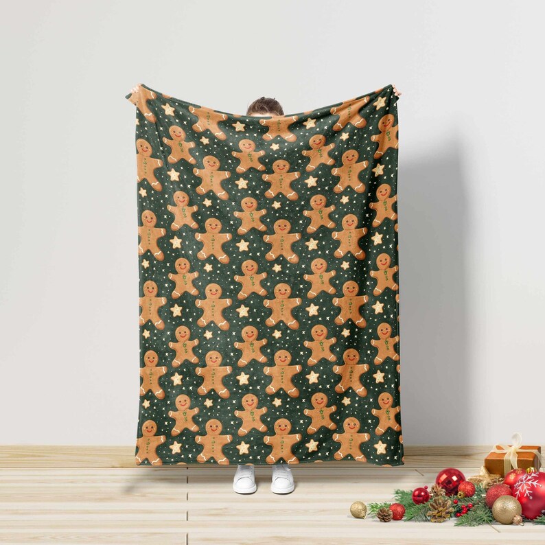 May include: A dark green blanket with a repeating pattern of gingerbread men and white stars. The gingerbread men are light brown with smiling faces. The blanket is made of a soft material.