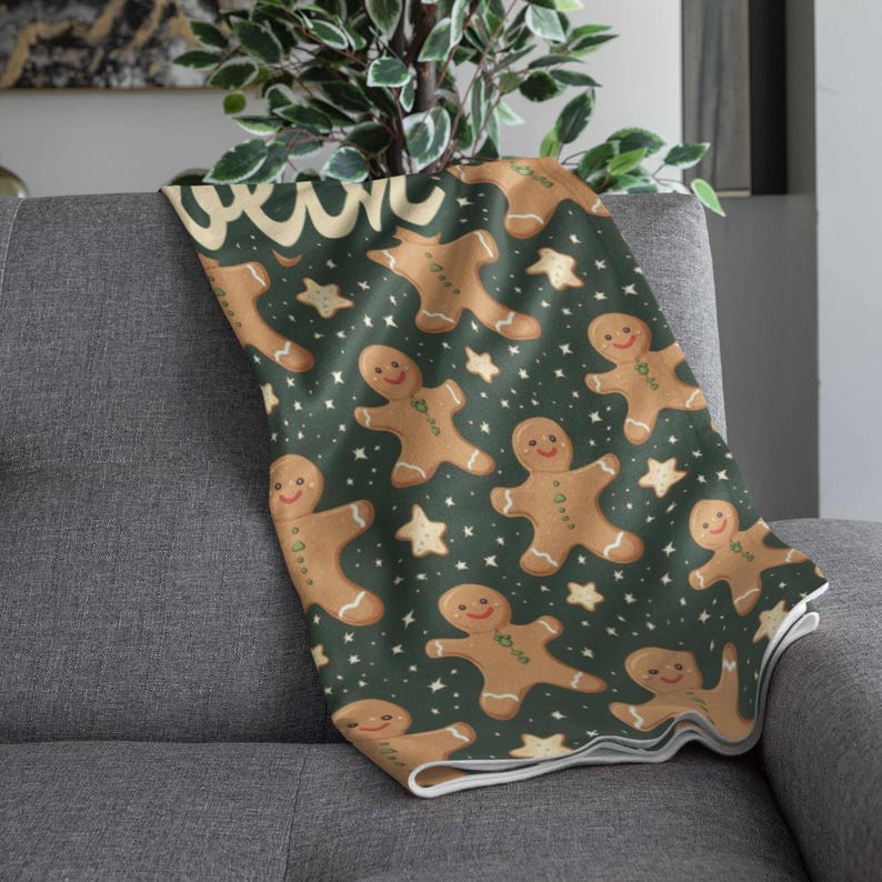 May include: A cozy throw blanket featuring a repeating pattern of gingerbread men and stars on a dark green background. The blanket is draped over a gray sofa, showcasing its festive design. The gingerbread men have smiling faces.