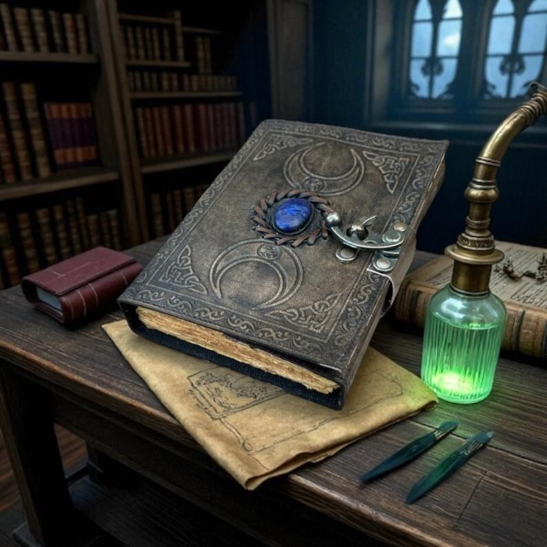 Pode incluir: Imagem detalhada de um livro encadernado em couro com desenhos de meia-lua e fecho de pedra azul. Um pequeno livro vermelho, uma garrafa de po&ccedil;&atilde;o verde e duas ferramentas verdes sobre uma mesa de madeira, tema de fantasia.