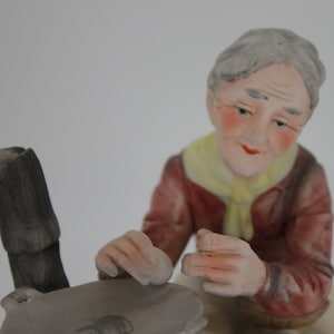 Femme vintage en porcelaine faisant la cuisine sur un réchaud à panse, vers les années 1960