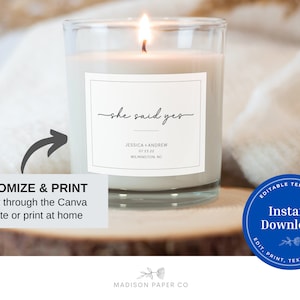 May include: A burning candle in a clear glass jar with a white label. The label says "she said yes" along with names, a date, and a city. The image includes text that says "Customize & Print" and "Instant Download."