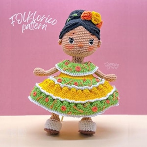 Puede incluir: Una muñeca de crochet vestida con un vestido amarillo y verde con detalles florales. La muñeca tiene el pelo negro y una corona de flores. El texto "Folklorico pattern" es visible en la esquina superior izquierda de la imagen.