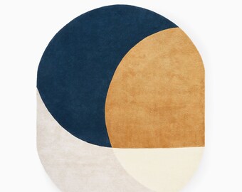 May include: A round rug with a geometric design in shades of blue, beige, and brown. The rug has a curved shape and is made of soft, plush material.