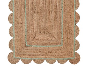Könnte beinhalten: Ein rechteckiger Jute-Teppich mit einem gewellten Rand. Der Teppich hat eine natürliche braune Farbe mit einem hellblauen Rand. Das Innendesign zeigt eine Reihe konzentrischer Rechtecke, die einen geschichteten Effekt erzeugen. Der Teppich ist für den Innenbereich geeignet.