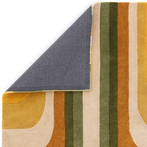May include: A colorful rug with a retro design. The rug features vertical stripes in shades of yellow, green, beige, and brown. A corner of the rug is lifted, revealing a gray backing with a green border. The rug has a soft, textured appearance.