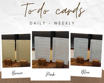 May include: Three sets of to-do cards, one in brown, one in pink, and one in blue. Each set includes a daily and weekly planner card. The cards are displayed on wooden stands.