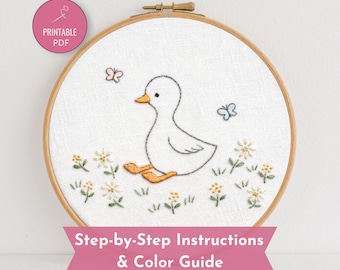 May include: A round wooden embroidery hoop containing white fabric with a hand-stitched design of a white duck with orange feet, surrounded by small white and yellow flowers and two butterflies. A pink circle icon reads PRINTABLE PDF.