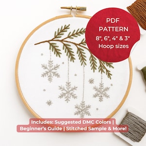 May include: An embroidery hoop with a white fabric featuring a stitched design of a branch with green leaves and silver snowflakes. The text on the red circle says "PDF PATTERN 8", 6", 4" & 3" Hoop sizes". Includes suggested DMC colors and a beginner's guide.