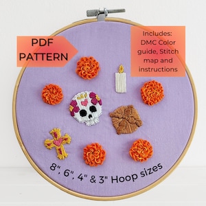 Könnte beinhalten: Ein lilafarbener Stickrahmen mit verschiedenen Stickmotiven, darunter ein Zucker Schädel, Ringelblumen, ein Kreuz, eine Kerze und ein Blatt. Der Rahmen ist mit dem Text "PDF PATTERN" und "8", 6", 4" & 3" Hoop sizes" beschriftet. Der Text "Includes: DMC Color guide, Stitch map and instructions" ist ebenfalls enthalten.