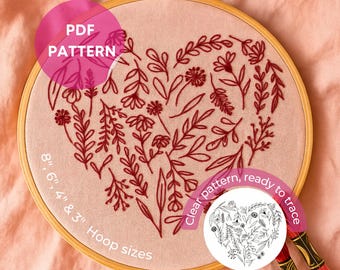 May include: A heart-shaped embroidery pattern featuring floral designs in red thread on a pink fabric. The design is held within a wooden embroidery hoop. Text on the image reads "PDF PATTERN" and "8", 6", 4" & 3" Hoop sizes".