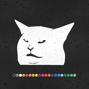 May include: A white cat meme sticker with a grumpy expression. The cat has a white background and is looking to the right. The sticker is on a black background with water droplets.