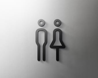 May include: Black restroom signs, a male and female symbol, are displayed against a light gray background. The male symbol is a simple outline of a person, and the female symbol is a skirted figure.