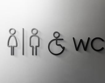 Può includere: Un cartello per i bagni in bianco e nero con icone per donne, uomini e accessibilità per sedie a rotelle. Il cartello include anche il testo "WC".