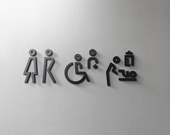 May include: A set of black restroom signs, including symbols for men, women, wheelchair accessibility, baby changing station, and a baby bottle. The signs are mounted on a light gray wall.