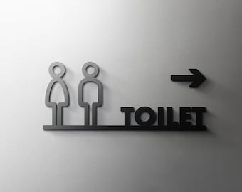 May include: Black and white sign with a stylized image of a man and woman, an arrow pointing right, and the word "TOILET" in bold letters.