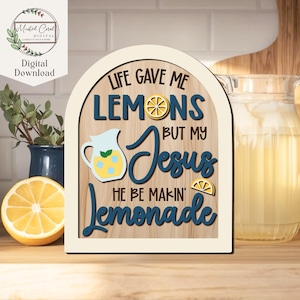May include: Wooden sign with the text "LIFE GAVE ME LEMONS BUT MY Jesus HE BE MAKIN' Lemonade". The sign features a lemon slice, a pitcher of lemonade, and a lemon slice. The sign is in a cream-colored frame.