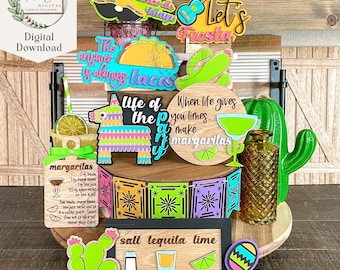 Könnte beinhalten: Ein Set aus bunten Holzschilden mit Fiesta-Thema. Die Schilder zeigen Sprüche wie "Happy Taco de Mayo", "Let's Fiesta", "The answer is always tacos", "Life of the Party", "When life gives you limes, make margaritas" und "Salt Tequila Lime Repeat". Außerdem gibt es eine Maraca, eine Piñata und ein Margarita-Rezept.