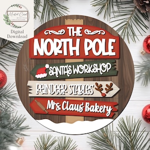 Puede incluir: Un letrero redondo de madera con temática navideña. El letrero presenta el texto "THE NORTH POLE" en blanco sobre un fondo rojo. Debajo hay letreros direccionales para "SANTA'S WORKSHOP", "REINDEER STABLES" y "Mrs. Claus Bakery".