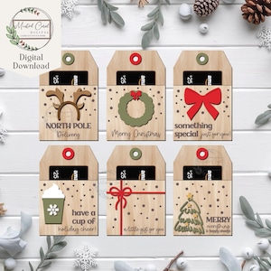 Può includere: Portacarte regalo in legno con disegni a tema festivo. Ogni supporto presenta un design diverso, tra cui una renna, una ghirlanda, un fiocco, una tazza di caffè, un regalo e un albero di Natale. Il testo include "North Pole Delivery", "Merry Christmas" e "something special just for you!"