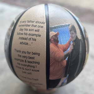 Op de afbeelding: Een witte basketbal met een zwarte streep en een foto van een vader en zoon erop. De basketbal heeft een citaat over vaders en zonen erop gedrukt: "Every father should remember that one day his son will follow his example instead of his advice..."  Het citaat wordt gevolgd door "Thank you for being the very best example & teaching me everything I know & don't know just yet! Love you Dad!"