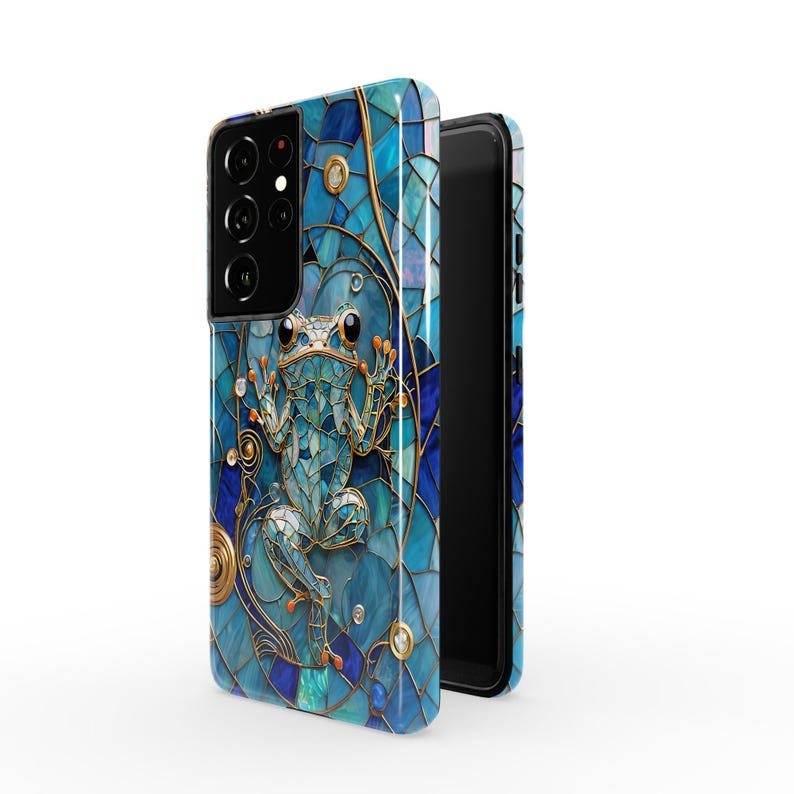 Peut inclure: Une coque de t&eacute;l&eacute;phone bleue et dor&eacute;e avec un motif de vitrail repr&eacute;sentant une grenouille. La coque est con&ccedil;ue pour un t&eacute;l&eacute;phone avec un triple objectif d'appareil photo.