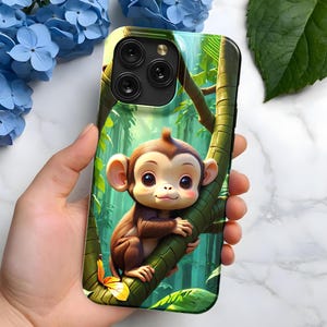 May include: A green, brown and yellow phone case featuring a cartoon monkey holding onto a vine. The monkey has brown fur, a light brown face and large blue eyes.